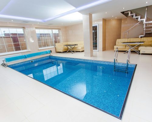 Luxurious indoor pool area featuring modern design and elegant furnishings.